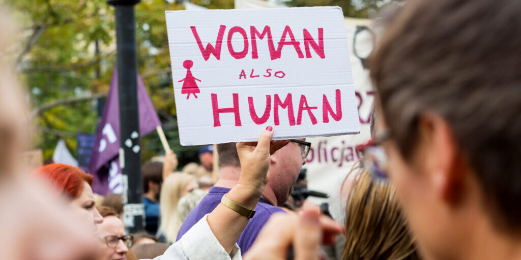Sign at protest that says "Woman, also human"